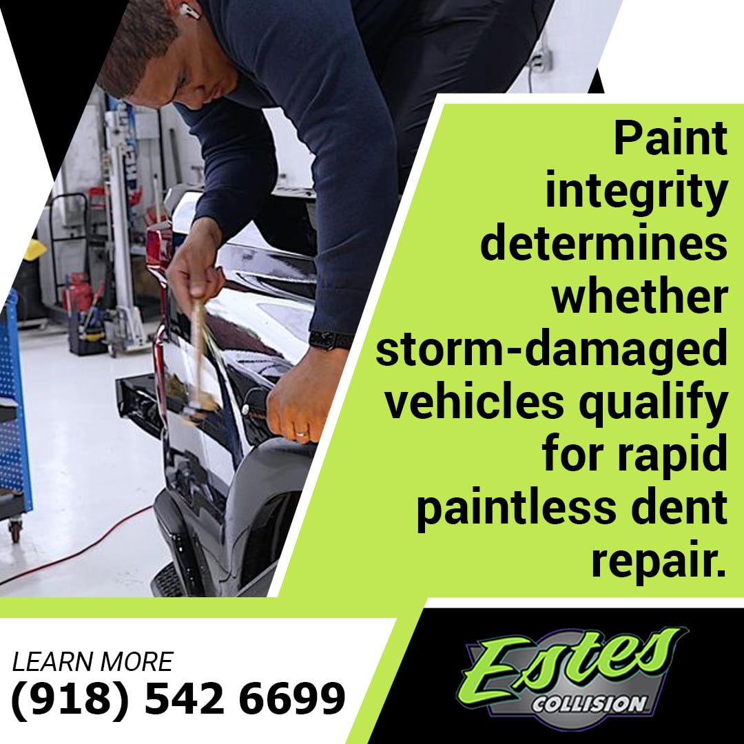 Auto body technician using a precision paintless dent repair blending hammer tool on the rear panel of a dark truck.