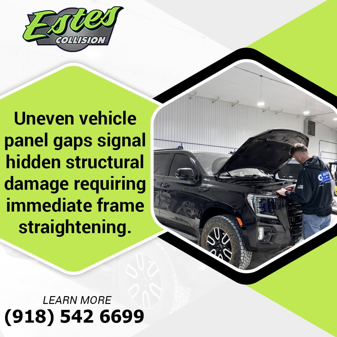 An auto technician inspecting the front hood and panel alignment of a black truck inside a collision repair shop.