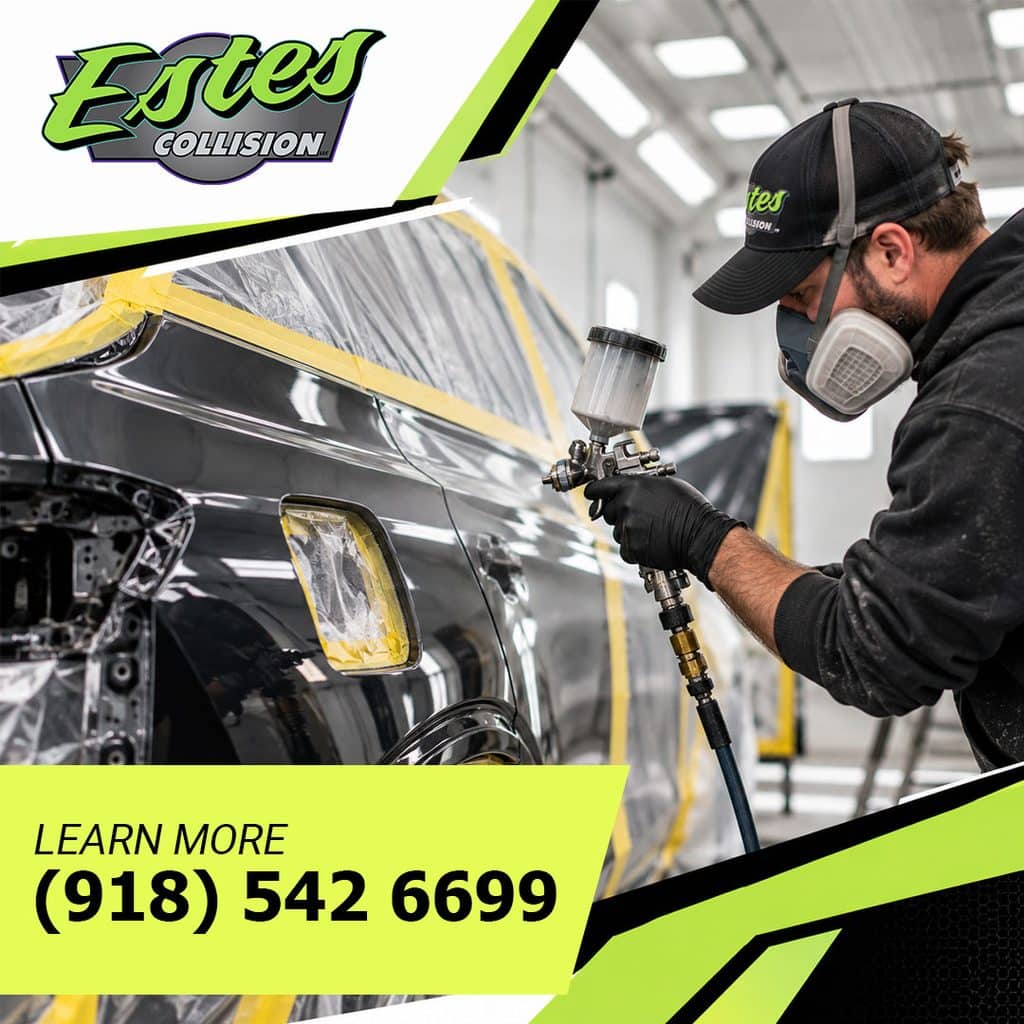 Technician in a respirator spraying paint on a masked dark vehicle inside a collision repair paint booth
